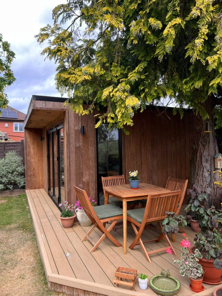 side view of garden office with decking and table and chairs