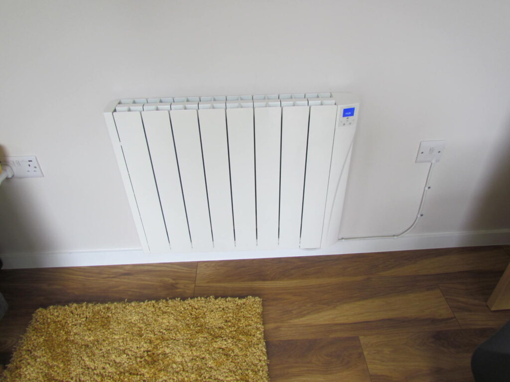 electric radiator on the wall with sockets and wooden floor