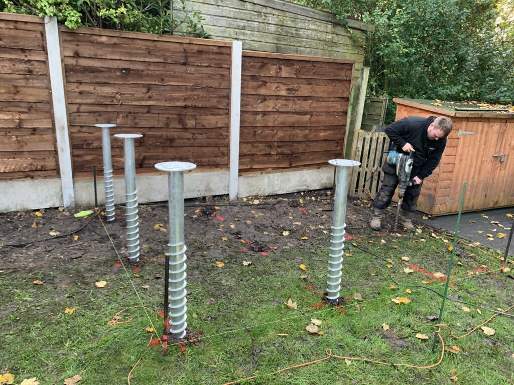 ground screws being installed by worker